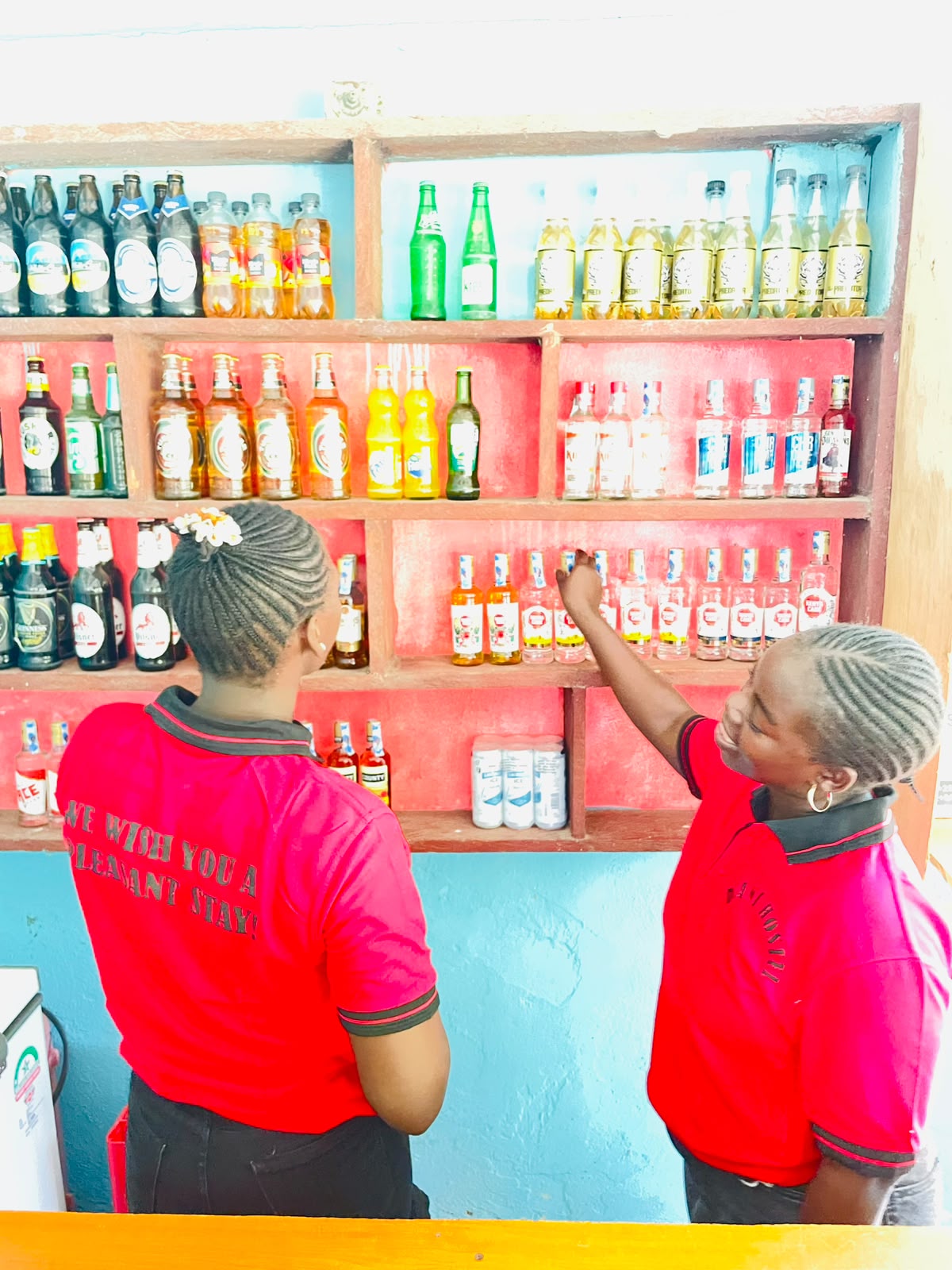 Diani Hostel bar staff restocking the drinks shelf behind the bar