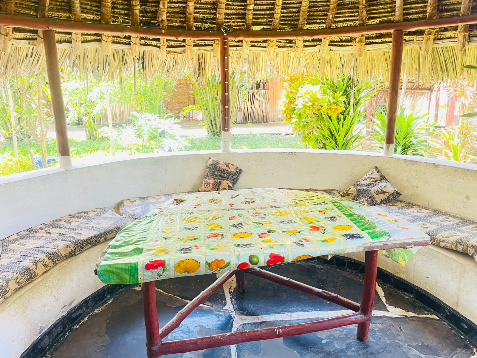 Cushioned bench seating and fruit print table under the makuti lounge roof